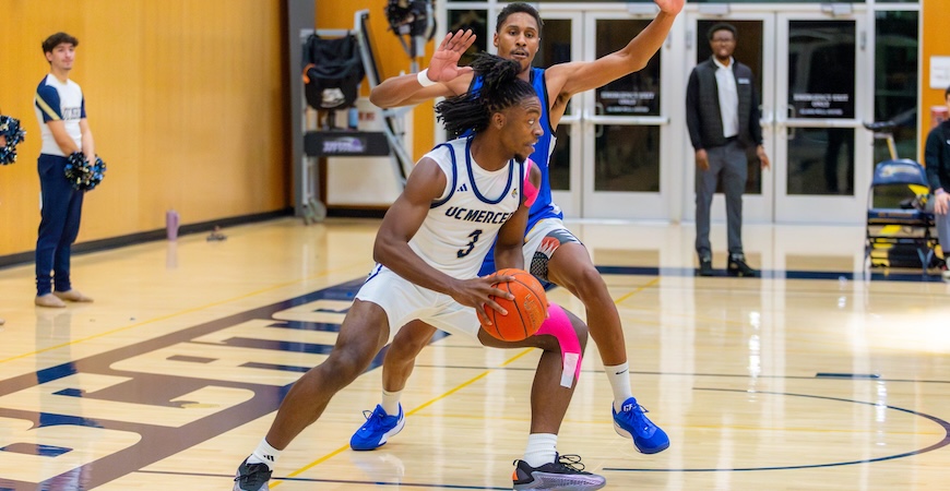 Photo depicts Myles Haynes looking to pass the ball to a teammate during a UC Merced basketball game.